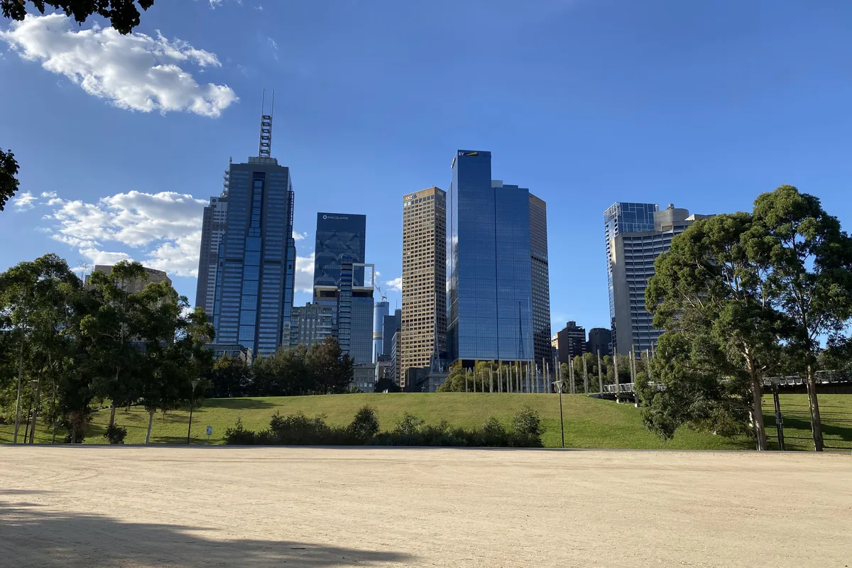 La pelouse de Birrarung Marr, avec les tours de la ville s'élevant derrière un bosquet d'eucalyptus.