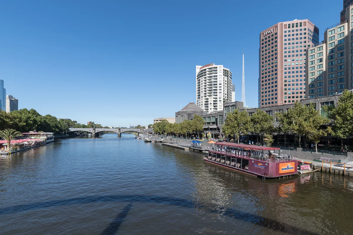 Le Yarra par temps clair, avec un bateau fluvial amarré à Southbank et des tours s'élevant le long de la rive.